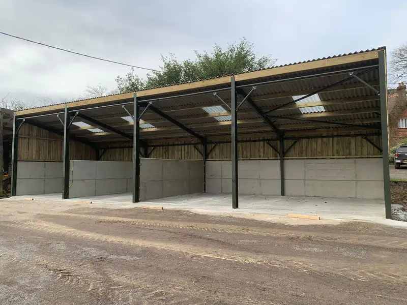 Open-front steel framed livestock building with concrete panels and roof lights